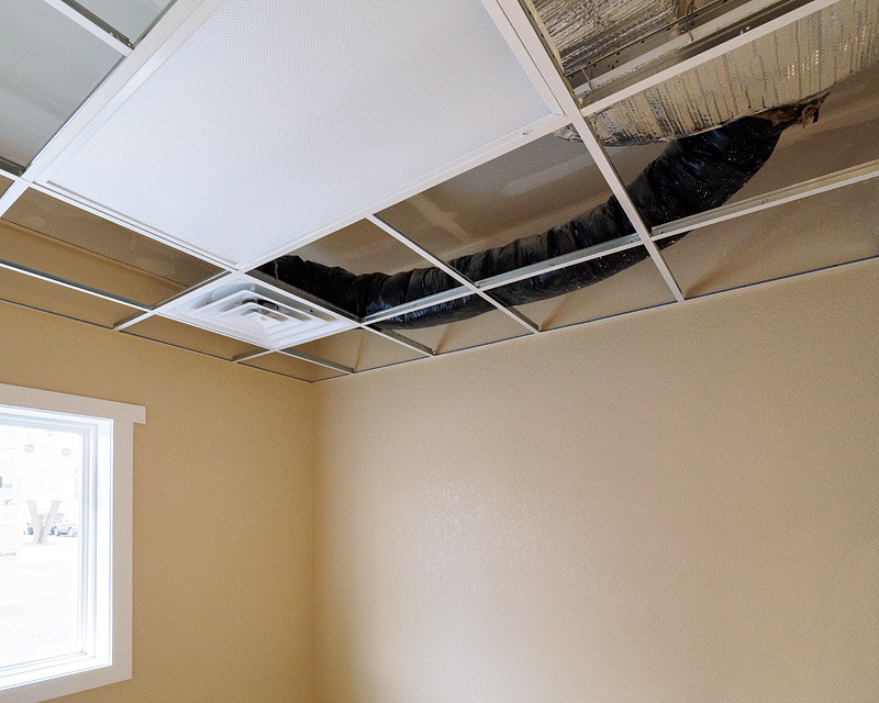 An air vent and flexduct in a drop ceiling.