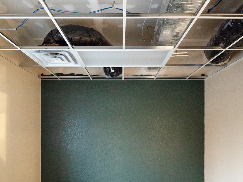 Metal ducts, flexduct, and an air vent in a drop ceiling in a new building.