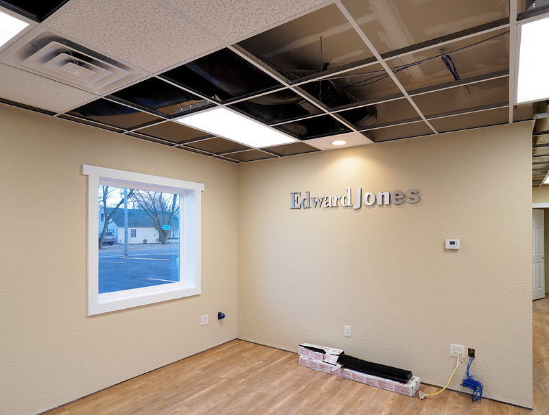 Digital thermostat on the wall and vents in the ceiling of the lobby of an office.