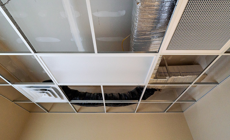 Metal air ducts installed above a drop ceiling in a commercial building under construction.